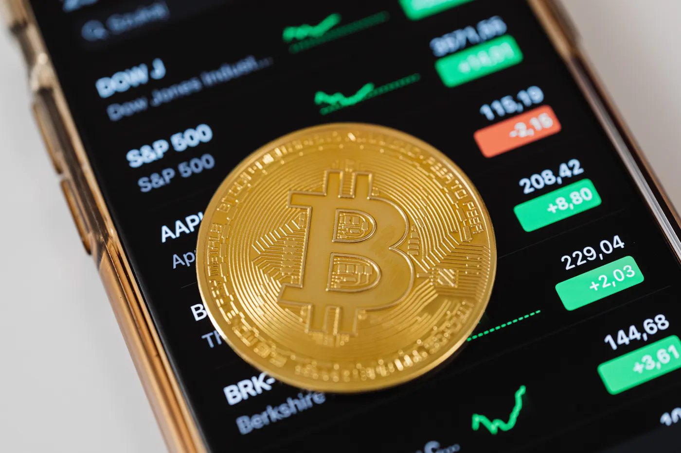 Bitcoin coin resting on a smartphone that displays momentum signals.