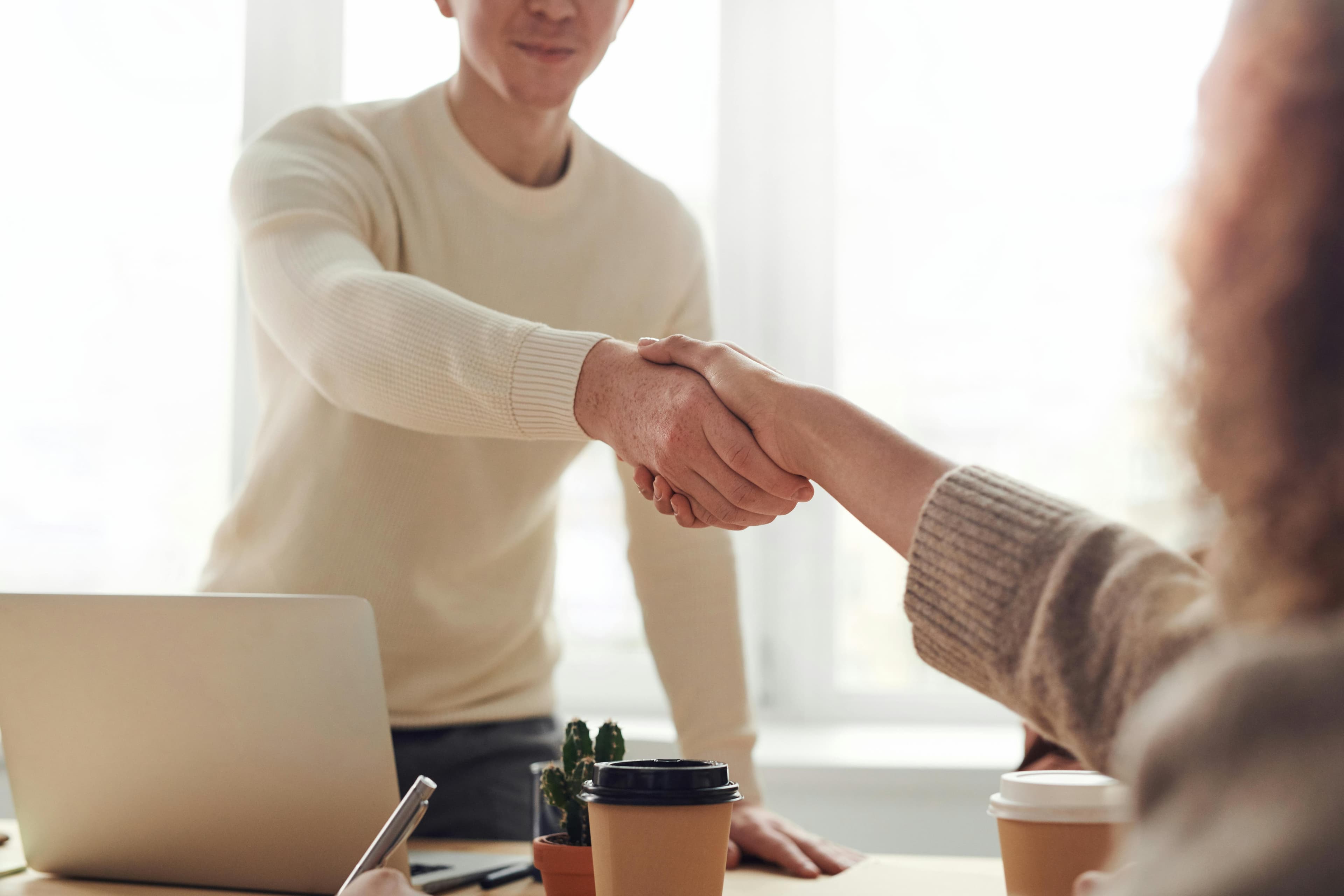 Executives shaking hands over a strategy session with notebooks on the table.